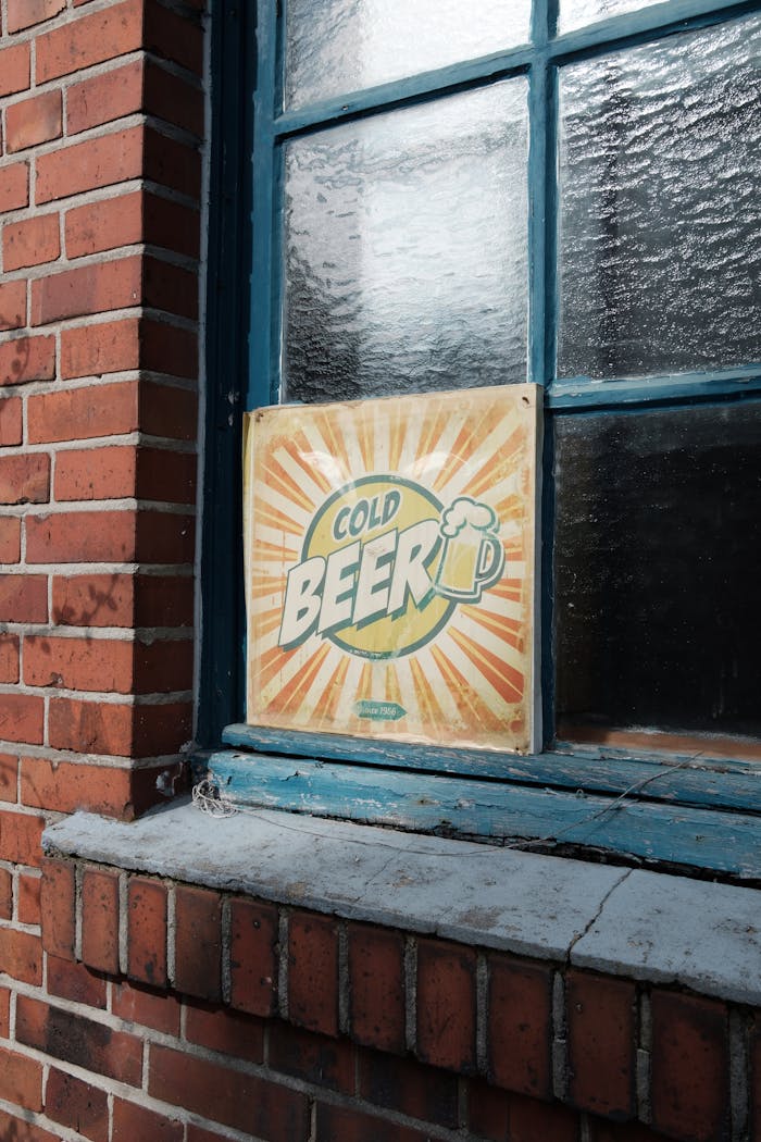 Vintage sign advertising cold beer on a window of a brick building in Coesfeld, Germany.